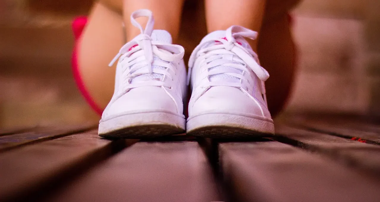 Paire de sneakers blanches posée sur un fond bois